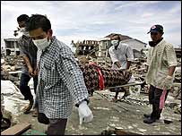 Relatives of 52-year-old Ainal Mardiah carry her body through the rubble in the center of Banda Aceh, Indonesia